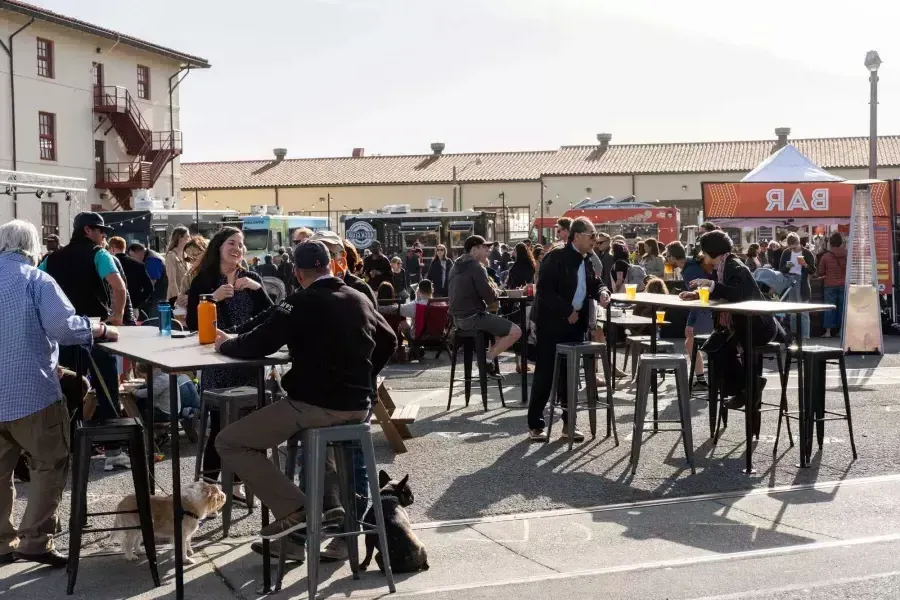 A crowd of people gather to eat at food trucks during 脱离电网 at Fort Mason Center.